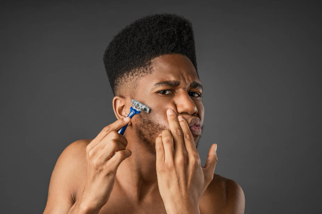 Afro-américain homme rasage son visage isolé sur fond gris
 - Photo, image