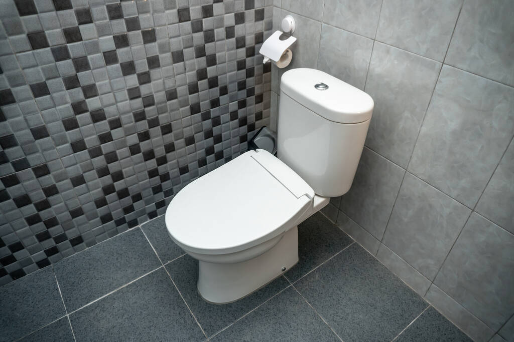 Foto einer weißen geschlossenen Toilette in einem Toilettenraum mit Keramikwänden - Foto, Bild
