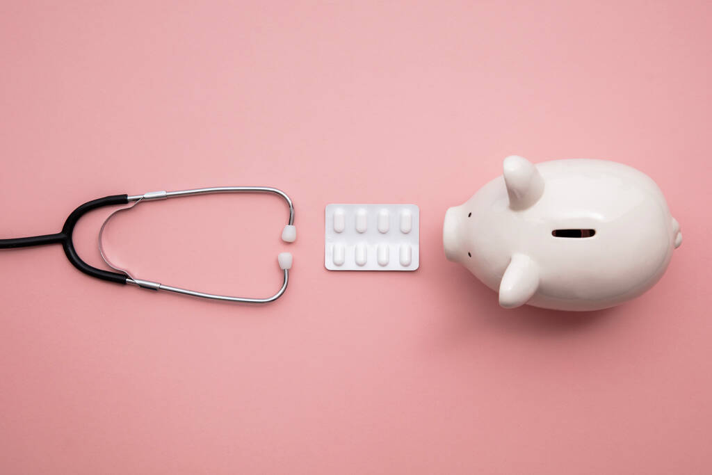 Gesundheitsfinanzierung. Medizinisches Stethoskop mit Sparschwein und Pillen - Foto, Bild
