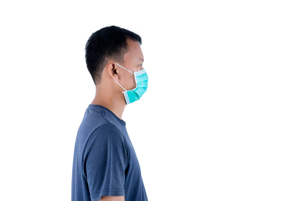 Side view of unknown man wearing medical mask while standing in studio, isolated on white background - Photo, Image