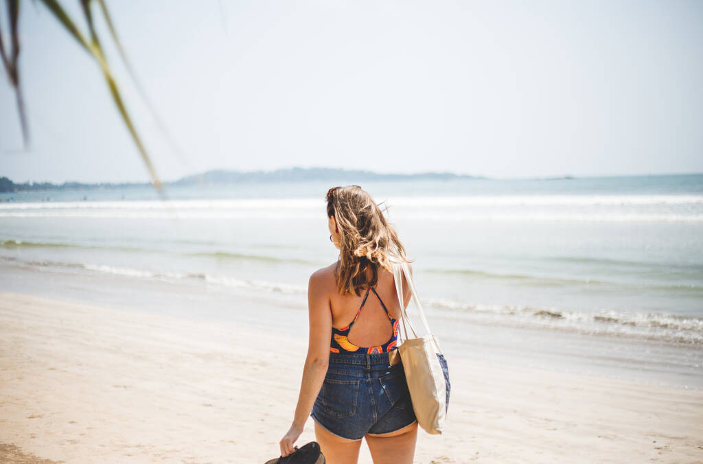 Schöne Frau im Bikini, die am Strand des Ozeans spazieren geht. Urlaub auf Reisen, Freiheit und Entspannung. - Foto, Bild