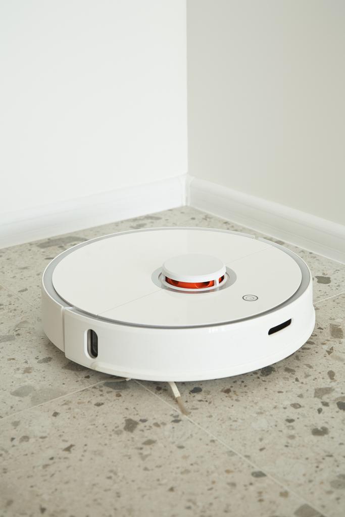 現代のロボット掃除機白い壁の近くの床のタイルを洗う  - 写真・画像