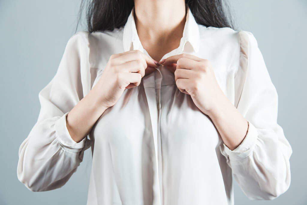 mano de mujer en botones de camisa sobre fondo gris
 - Foto, imagen