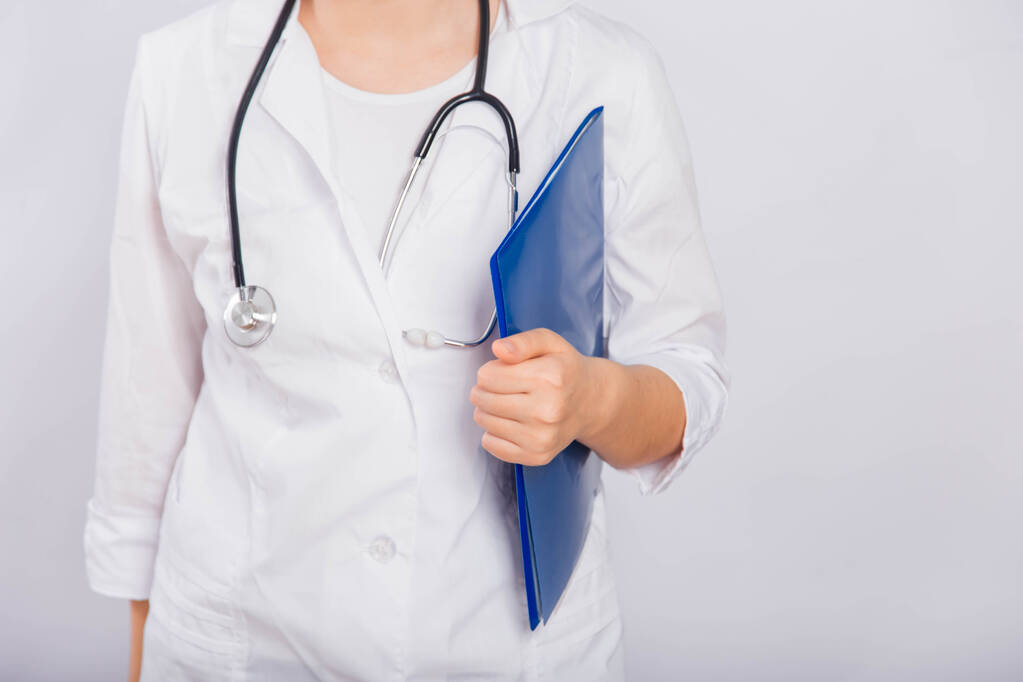 Close-up of a doctor's hand holding a blue folder, a young woman in a white coat on a white background, copy space. - Photo, Image