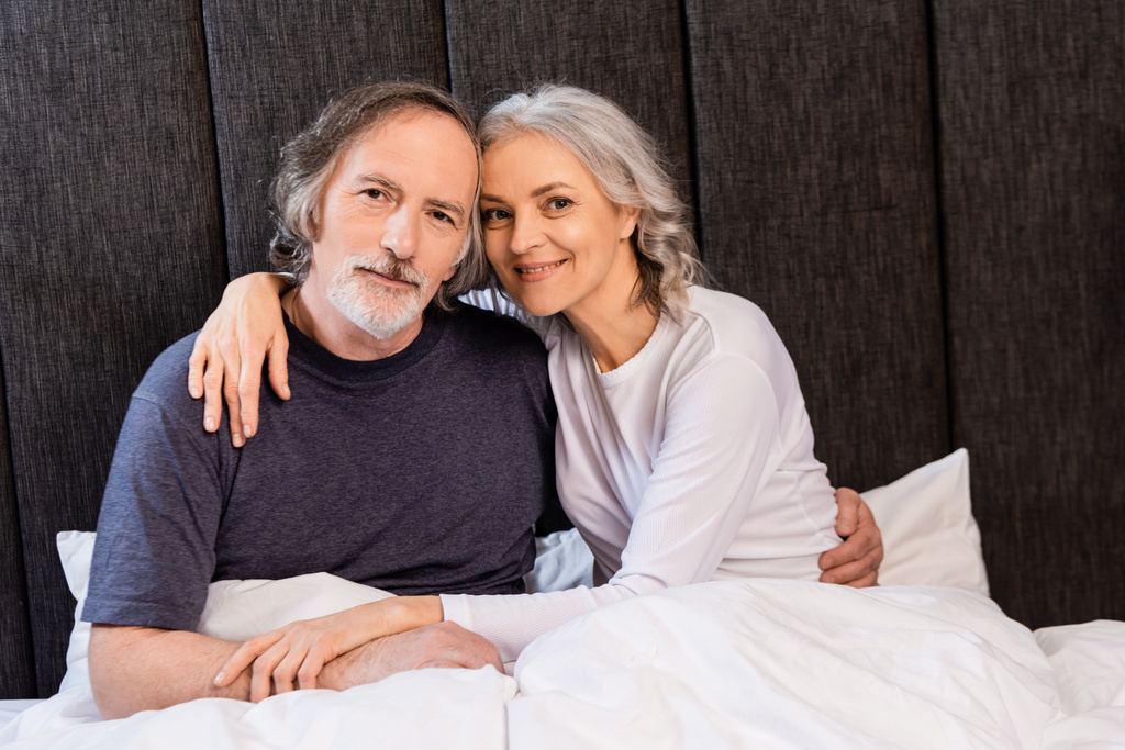 veselý dospělý pár objímání a usmívání v posteli  - Fotografie, Obrázek