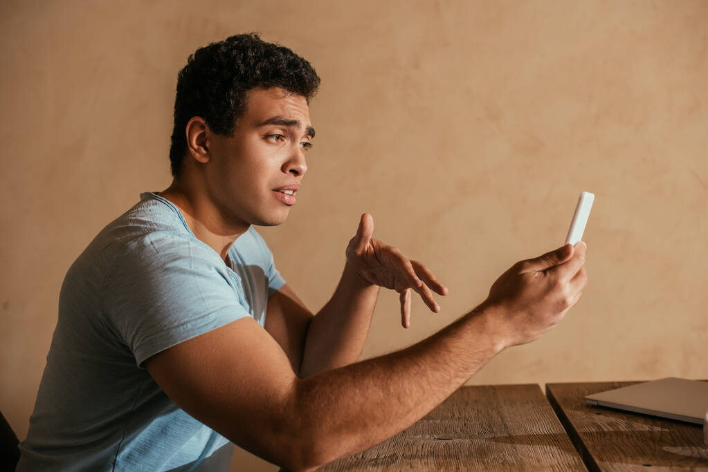 молодий змішаний чоловік має відеодзвінок на смартфон вдома на карантині
 - Фото, зображення