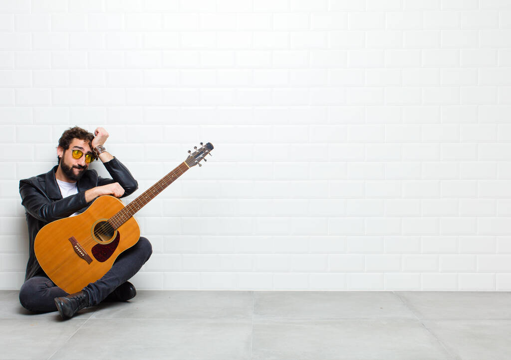 mladý muž s kytarou na podlaze v pokoji - Fotografie, Obrázek