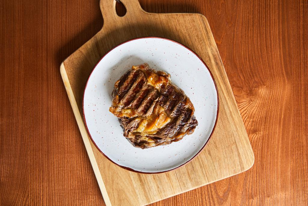 top view of fresh grilled steak on plate on cutting board on wooden table - Photo, Image