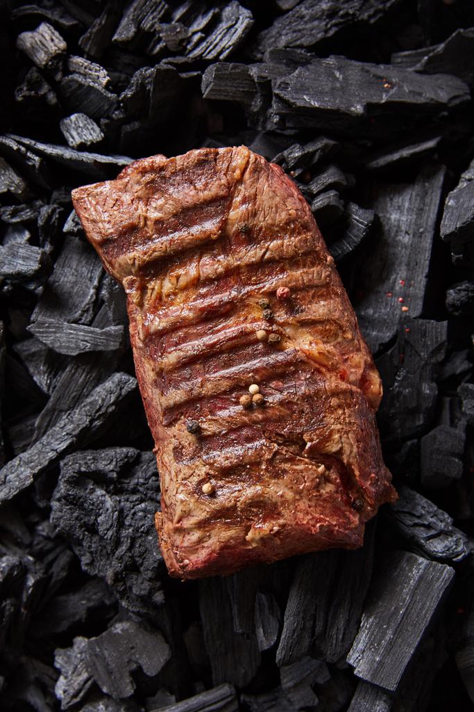vrchní pohled na čerstvě grilovaný chutný steak na černém uhlí - Fotografie, Obrázek