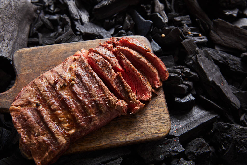 felülnézet vágott friss grillezett ízletes steak ritka pörkölt fa vágódeszka fekete szén - Fotó, kép