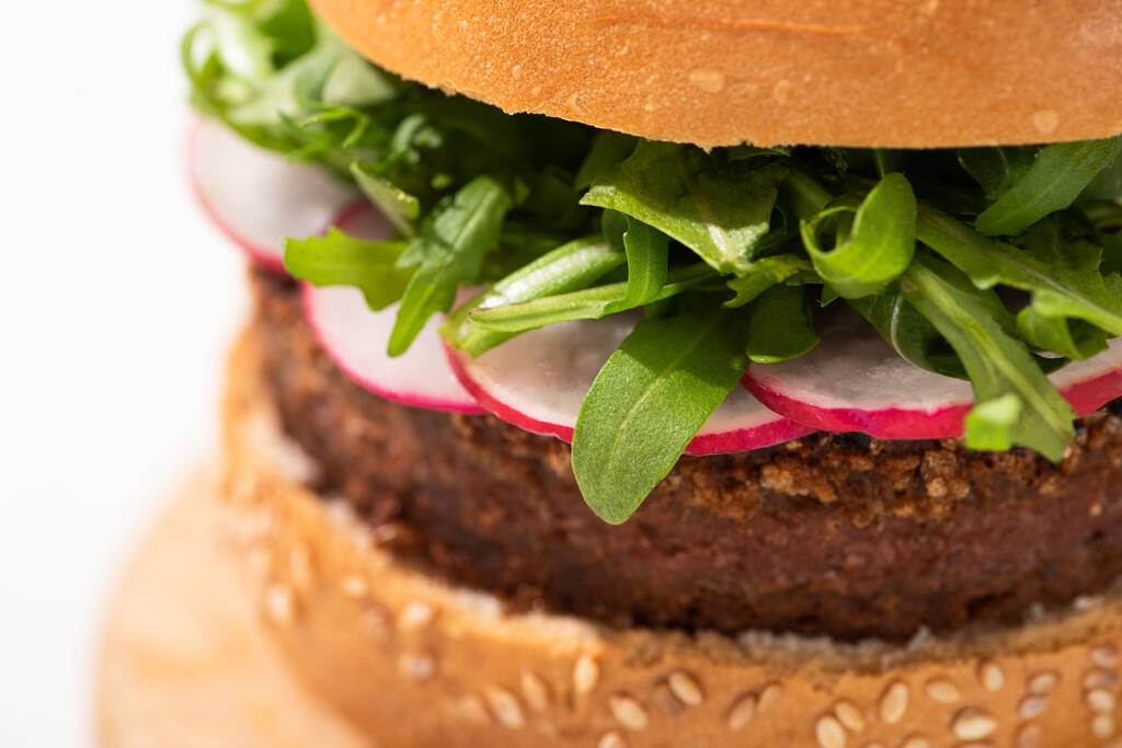 vista de cerca de deliciosa hamburguesa vegana con rábano y rúcula sobre fondo blanco
 - Foto, imagen