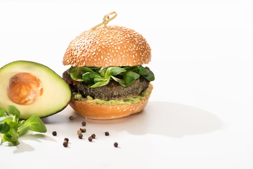 heerlijke groene veganistische hamburger met microgreens, avocado, zwarte peper op witte achtergrond - Foto, afbeelding