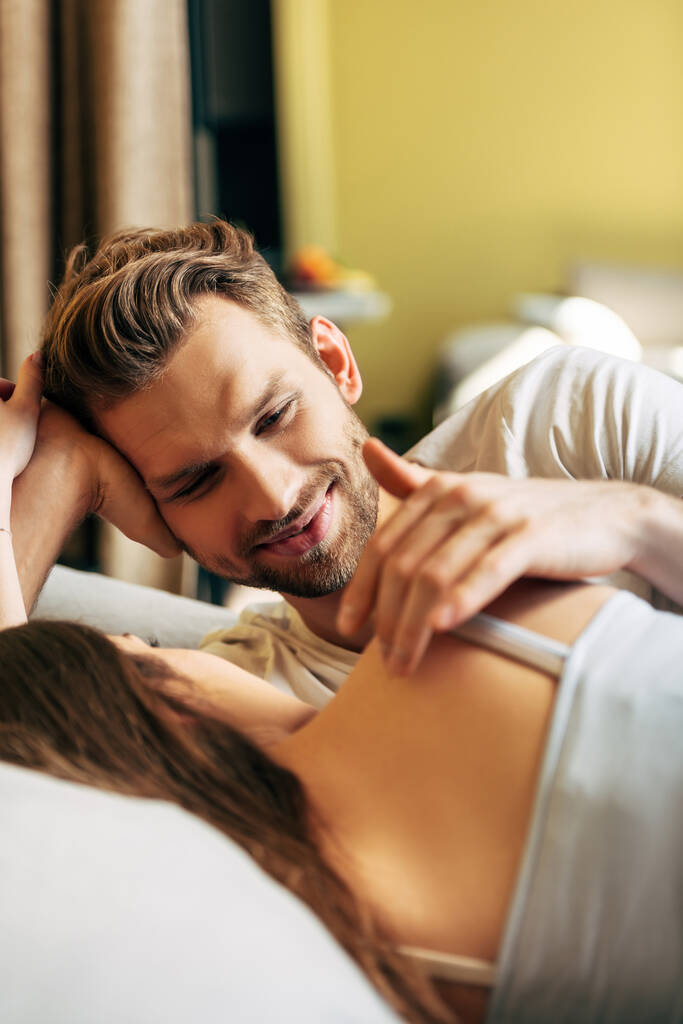 Selektiver Fokus eines gutaussehenden bärtigen Mannes, der seine Freundin im Bett ansieht - Foto, Bild