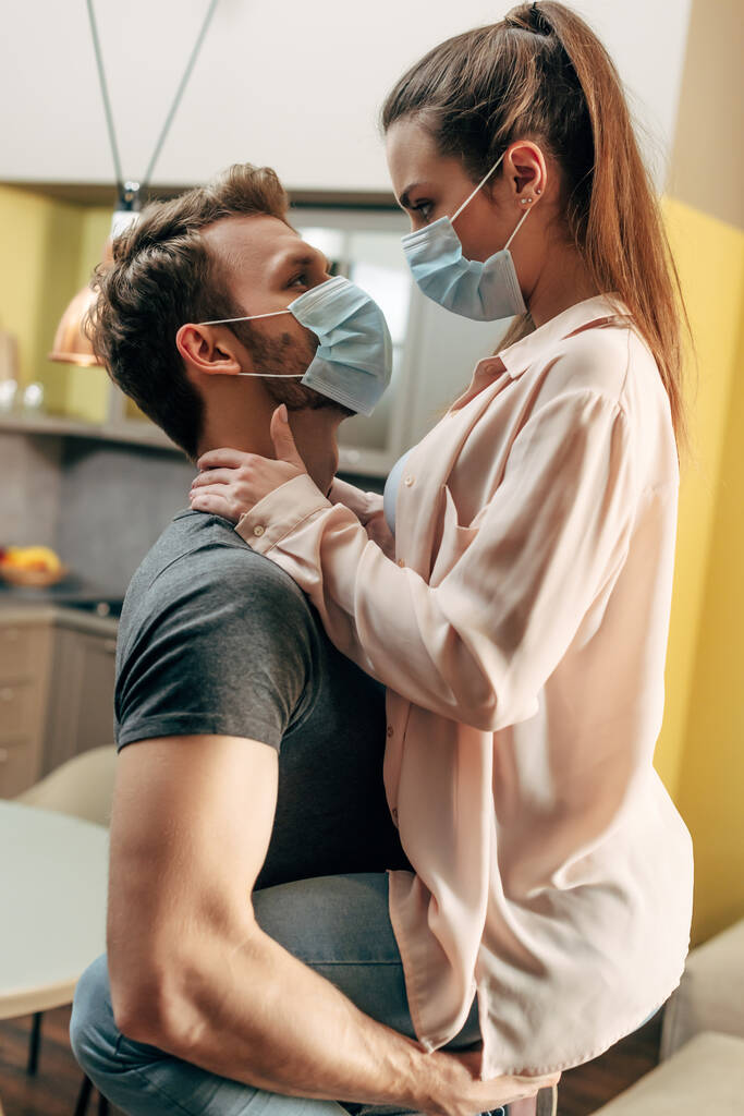 homem em máscara médica segurando em braços menina na sala de estar
  - Foto, Imagem