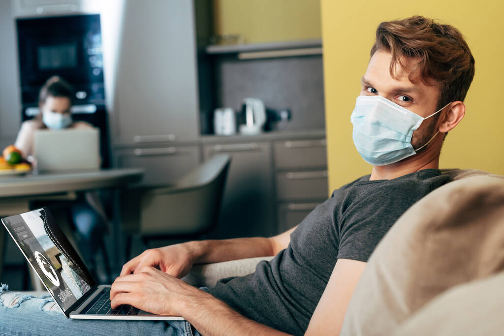 foyer sélectif de pigiste dans le masque médical à l'aide d'un ordinateur portable avec site de réservation près de petite amie
  - Photo, image