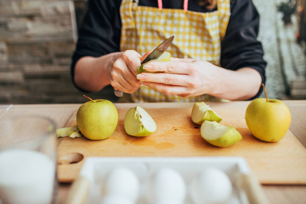 Шарлотта яблочный пирог выпечки - повар очищает и режет яблоки для начинки
 - Фото, изображение