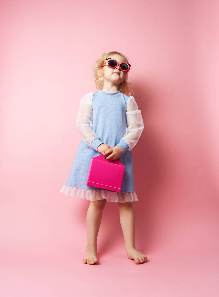 Kislány gyermek napszemüvegben, rózsaszín vöröscsővel. - Fotó, kép