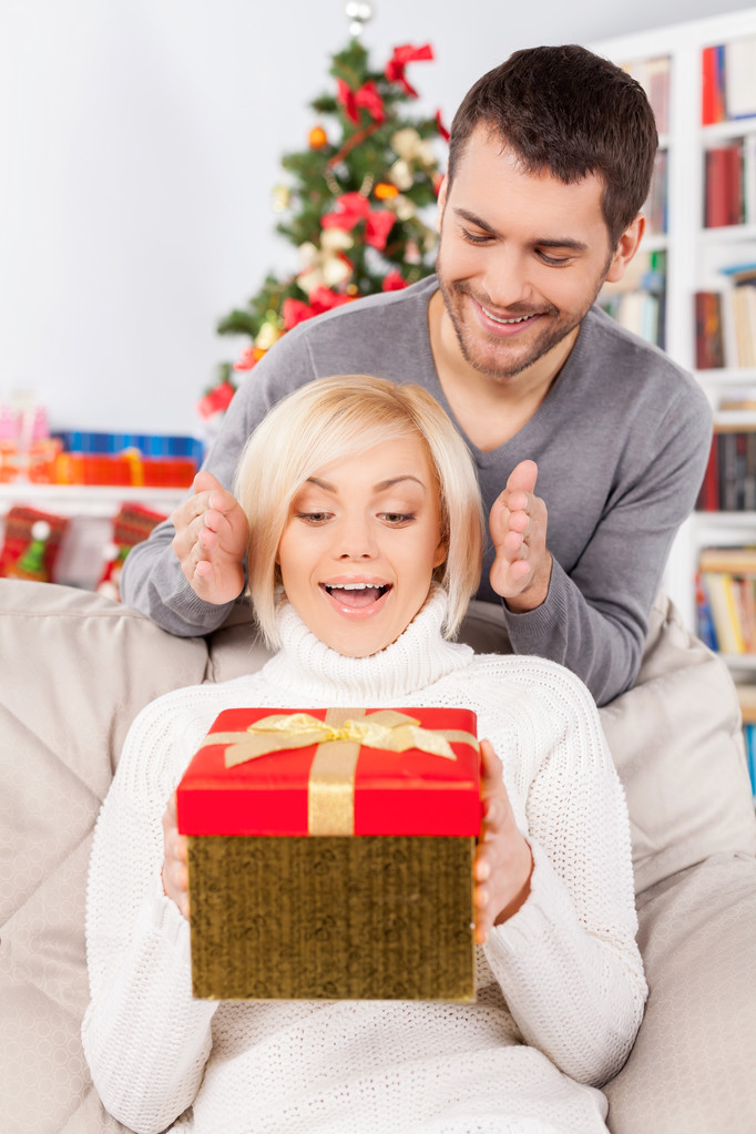 Mujer sosteniendo una caja de regalo mientras su novio sonríe
 - Foto, Imagen