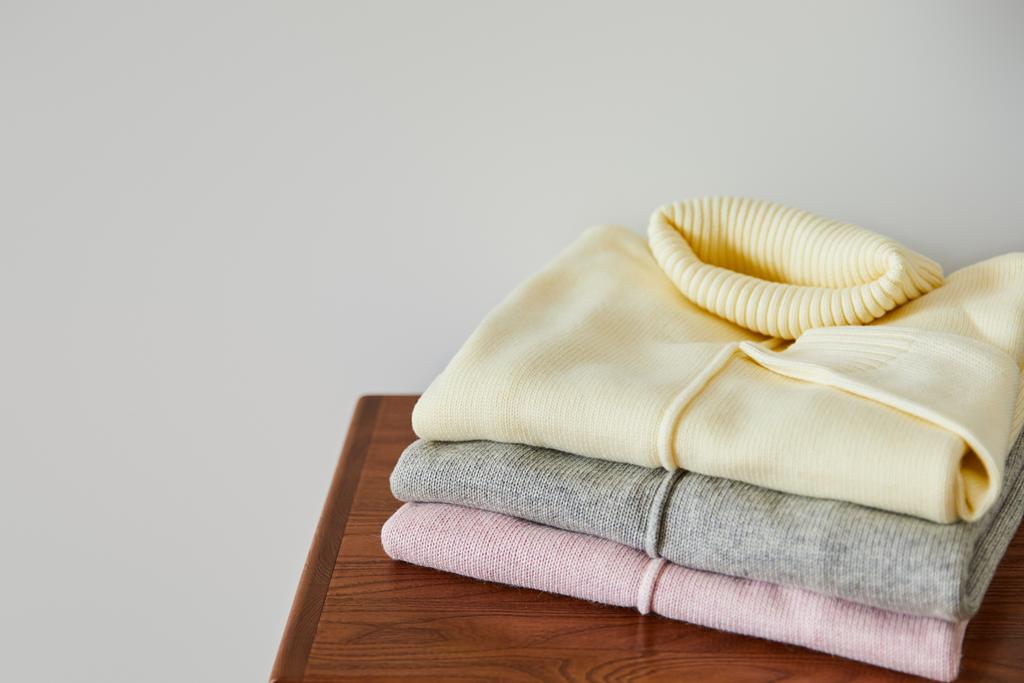pull doux tricoté rose, beige et gris sur table en bois isolé sur blanc
 - Photo, image