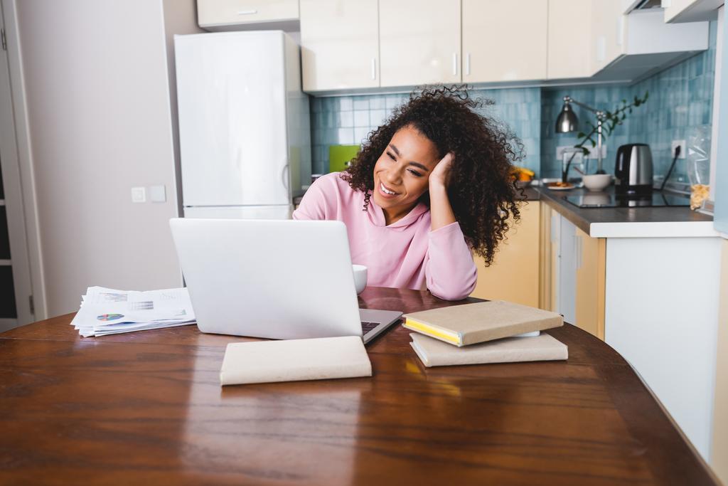 επιλεκτική εστίαση της ευτυχούς Αφρικής Αμερικανός ελεύθερος επαγγελματίας χρησιμοποιώντας φορητό υπολογιστή, ενώ εργάζονται από το σπίτι  - Φωτογραφία, εικόνα