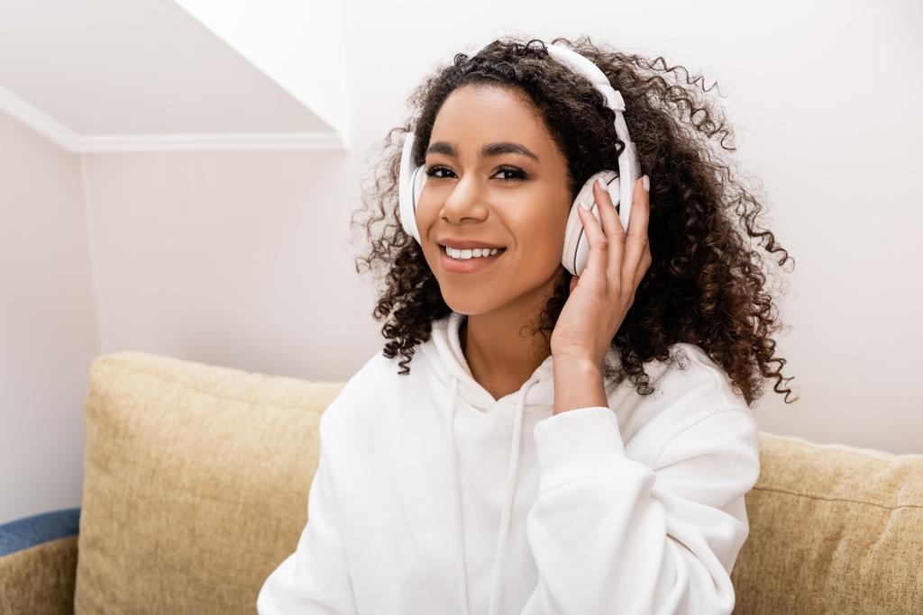 chica afroamericana feliz en auriculares inalámbricos escuchando música en casa
  - Foto, Imagen