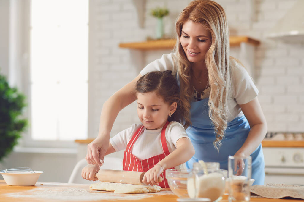 Matka i córka przygotowują mąkę wypieki na stole w kuchni. Szczęśliwego Dnia Matki - Zdjęcie, obraz