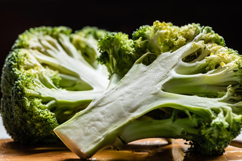 close up view of fresh green cut broccoli on wooden cutting board isolated on black - Photo, Image