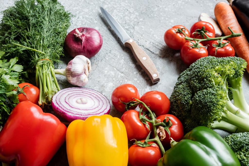 πολύχρωμα φρέσκα ώριμα λαχανικά με μαχαίρι σε γκρι τσιμεντένια επιφάνεια - Φωτογραφία, εικόνα