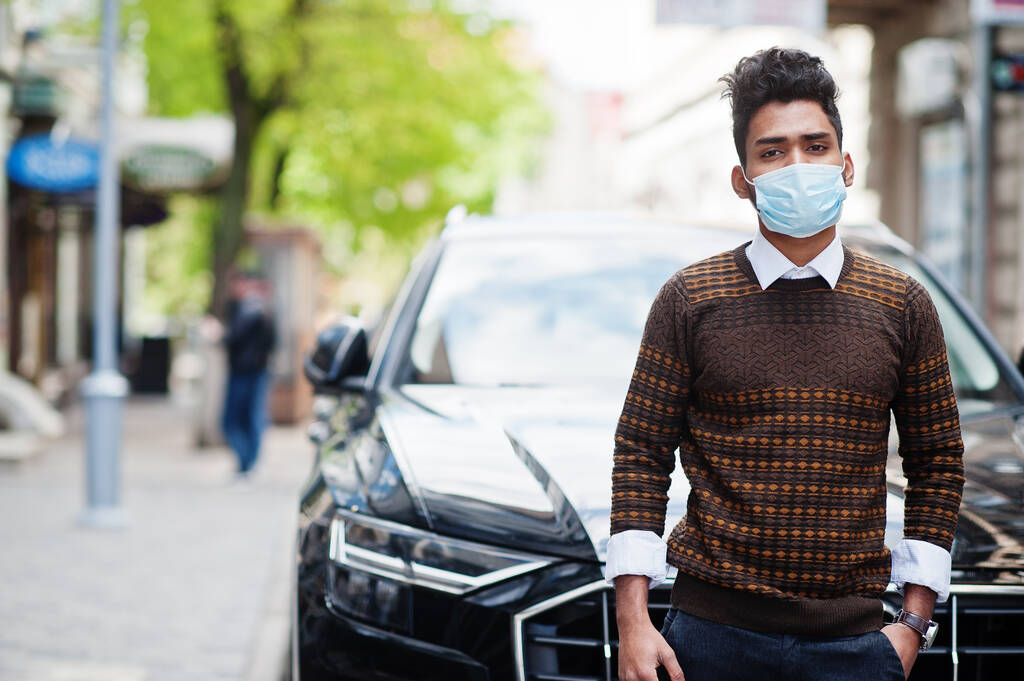Coronavirus covid-19 concept. Homme indien sud-asiatique portant un masque pour protéger contre le virus de la couronne posé contre la voiture d'affaires
. - Photo, image