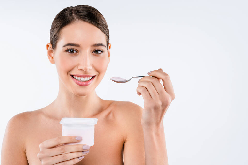 Schattige vrouwelijke eten yoghurt geïsoleerd over witte achtergrond - Foto, afbeelding