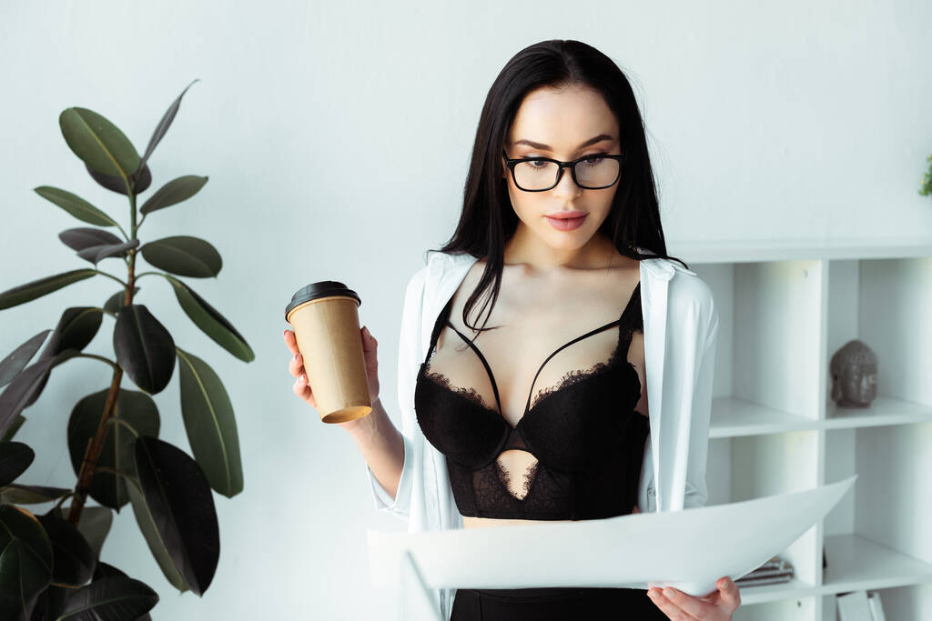 Enfoque selectivo de la sensual secretaria sosteniendo taza de papel y documentos en la oficina
  - Foto, Imagen