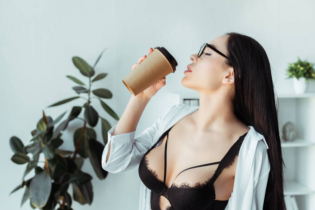 Sexy secretaria en anteojos y sujetador sosteniendo café para ir en la oficina
  - Foto, Imagen