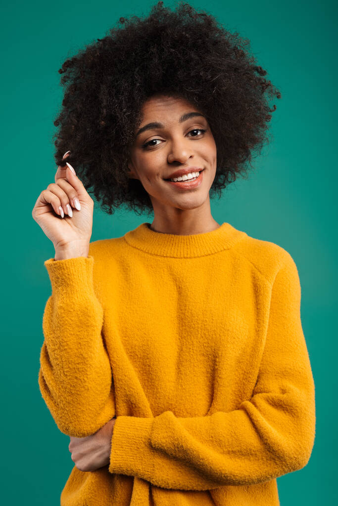 Portret uśmiechniętej, młodej Afrykanki noszącej sweter stojącej na zielonym tle, flirtującej - Zdjęcie, obraz