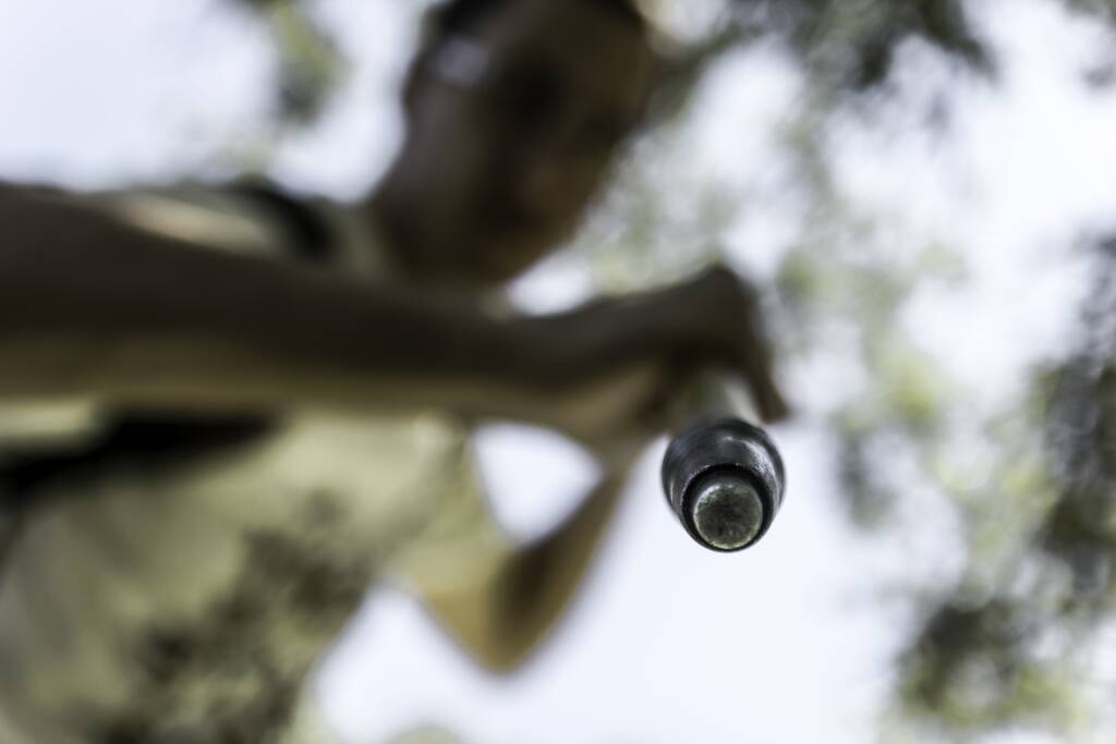 Um tiro seletivo do foco de uma vara de metal nas mãos de um macho sob a luz solar durante o dia
 - Foto, Imagem