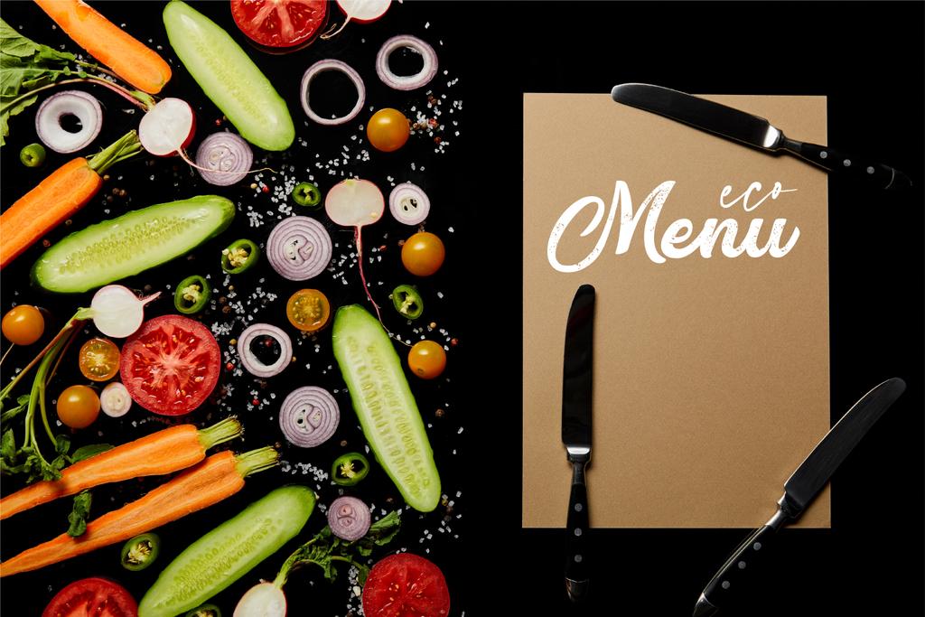 vue du dessus des tranches de légumes frais avec sel près de la carte de papier avec illustration de menu et couteaux isolés sur noir
  - Photo, image