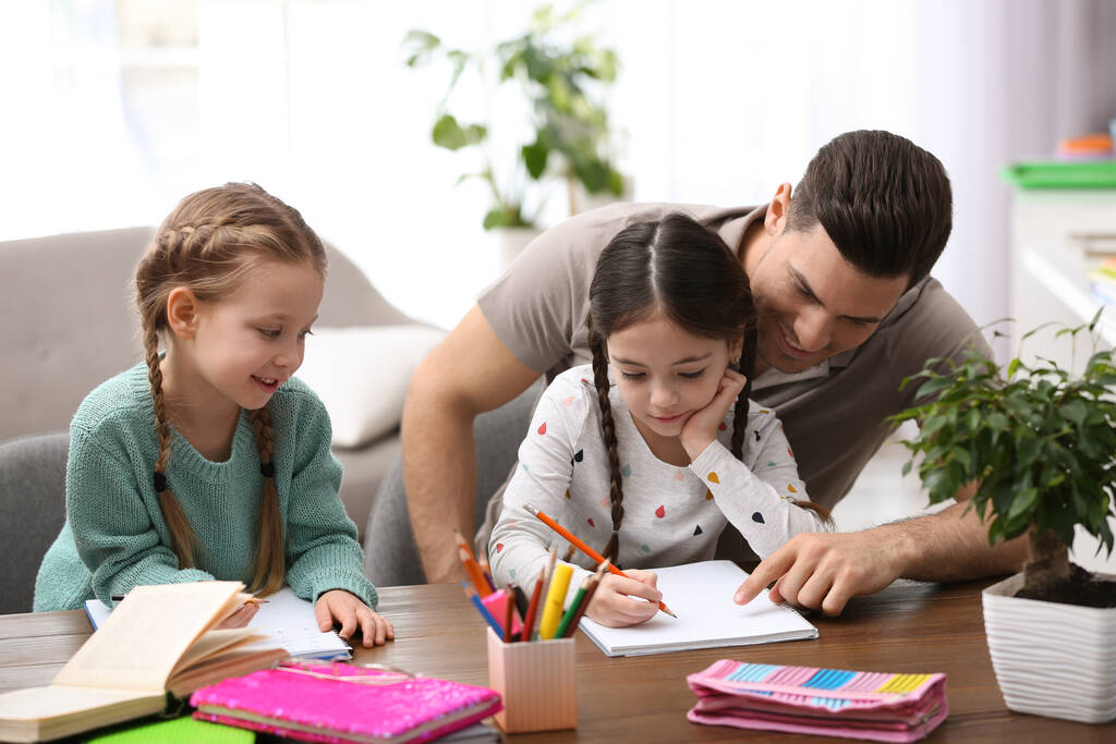 Père aidant ses filles avec des devoirs à table à l'intérieur
 - Photo, image