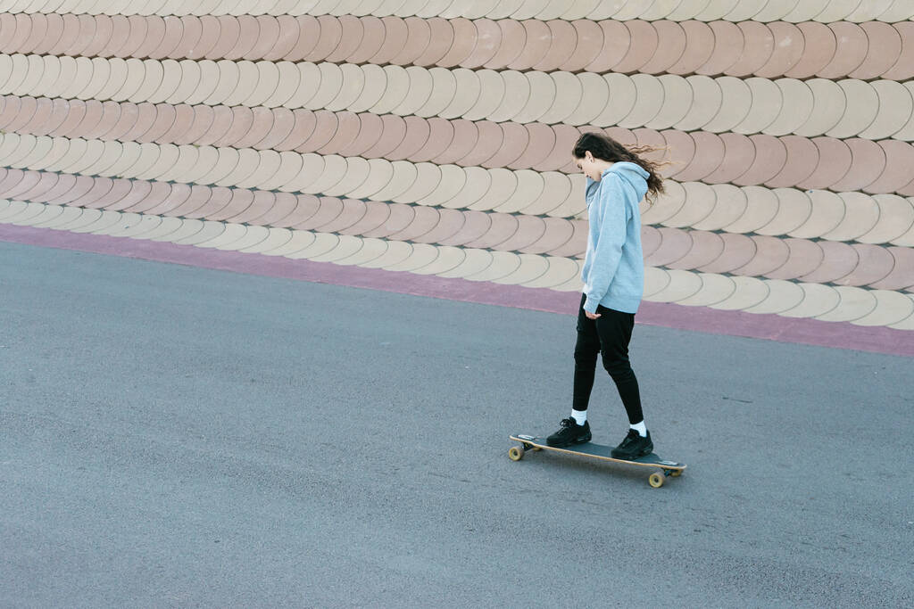 Adolescente patinant sur un longboard dans un parc de la ville par une journée ensoleillée
 - Photo, image