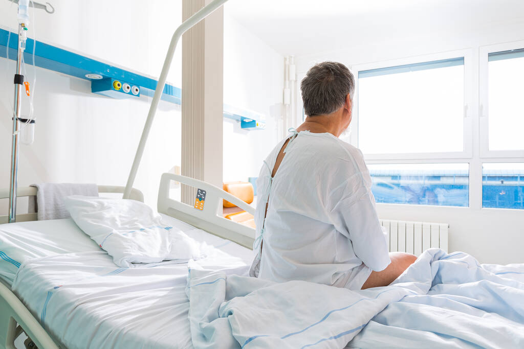 Modern bir hastanede kıdemli bir erkek hasta. Bir ameliyat / hastalık sonrası iyileşme (sığ DOF; renk tonlu resim) - Fotoğraf, Görsel