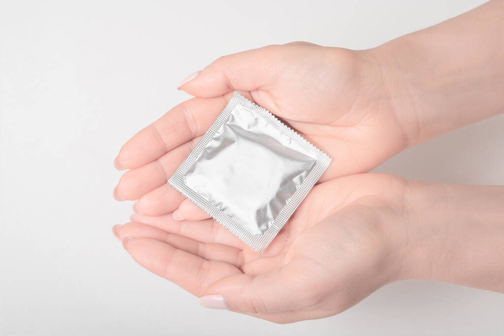 Gros plan femme main tenant préservatif, soins de santé et concept médical sur fond gris
 - Photo, image