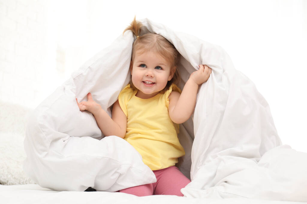 Niedliches kleines Kind spielt unter Decke im Bett - Foto, Bild