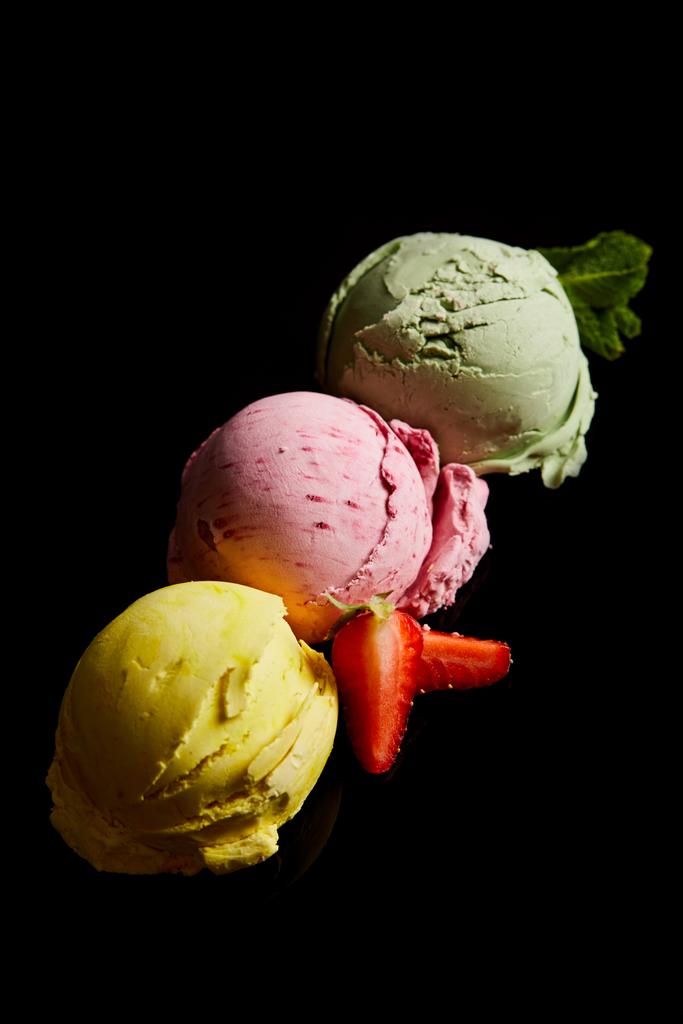 deliciosas bolas de helado de limón, fresa y menta aisladas en negro
 - Foto, imagen