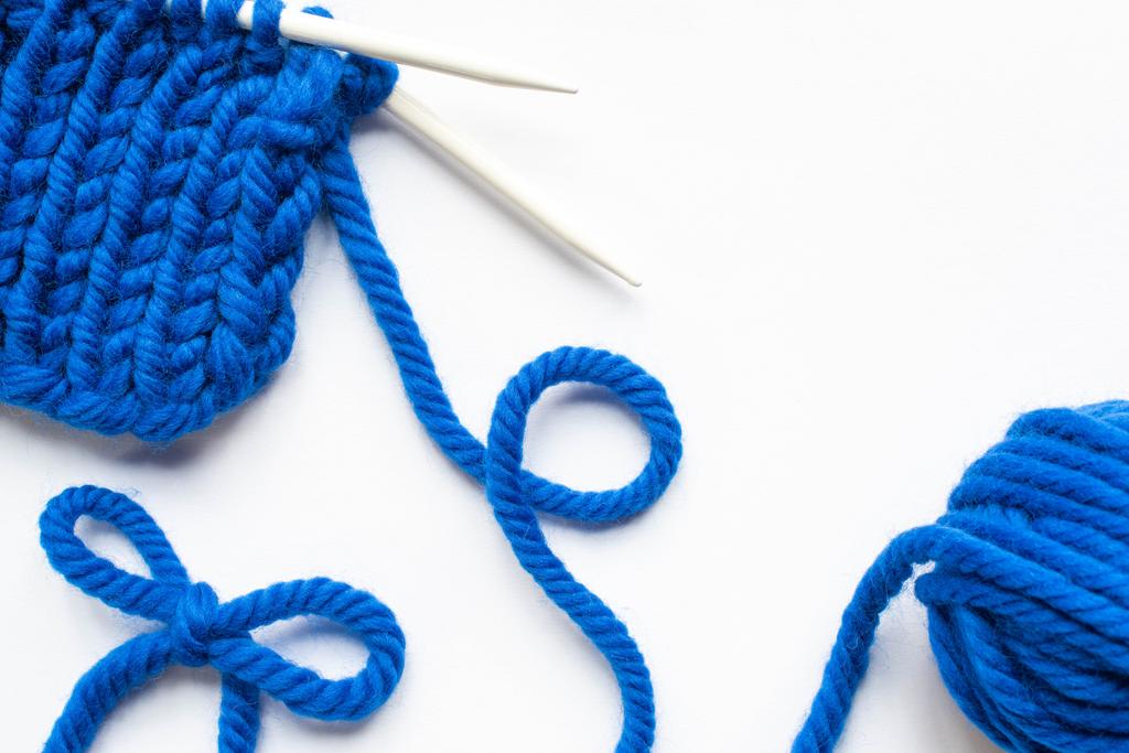 hilo de lana azul y agujas de punto sobre fondo blanco
 - Foto, imagen