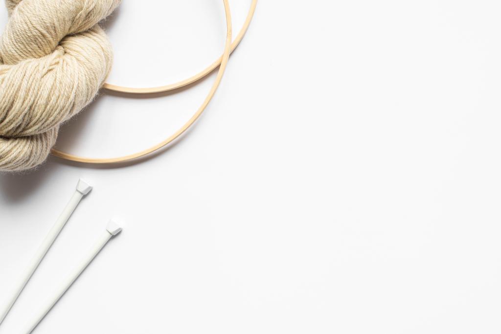 vue de dessus du fil beige et des aiguilles à tricoter et métiers à tisser sur fond blanc avec espace de copie
 - Photo, image