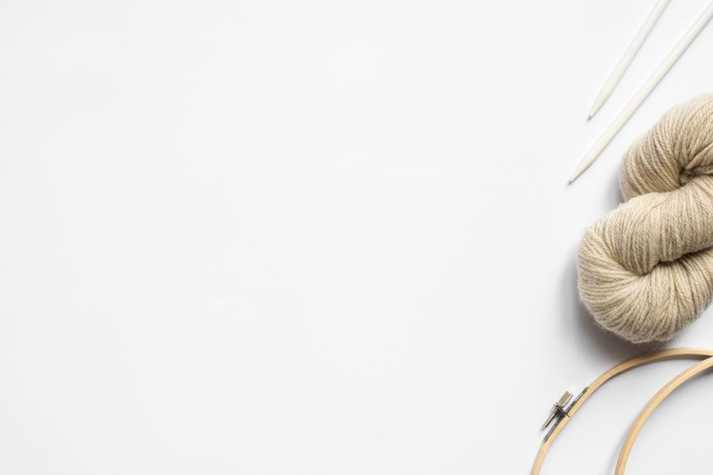 vue de dessus du fil beige et des aiguilles à tricoter et métiers à tisser sur fond blanc avec espace de copie
 - Photo, image