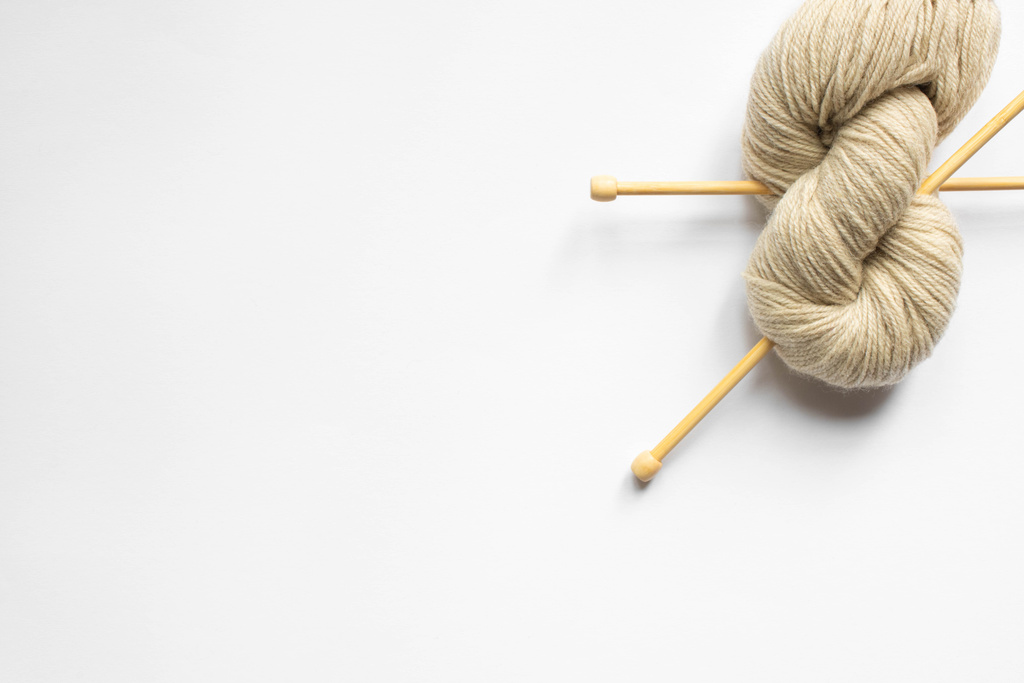 vue du dessus des fils de laine beige et des aiguilles à tricoter sur fond blanc
 - Photo, image