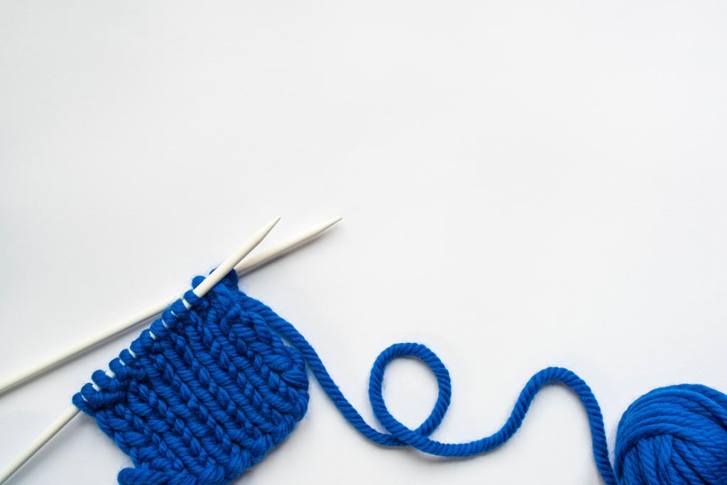 vista dall'alto di filo di lana blu e ferri da maglia su sfondo bianco
 - Foto, immagini