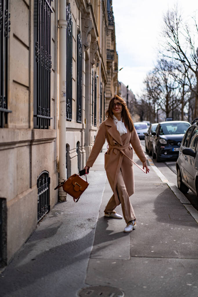 Μια νεαρή όμορφη γυναίκα περπατάει στο δρόμο, στο Παρίσι. Η έννοια μιας χαρούμενης ταξιδιωτικής φωτογραφίας. - Φωτογραφία, εικόνα