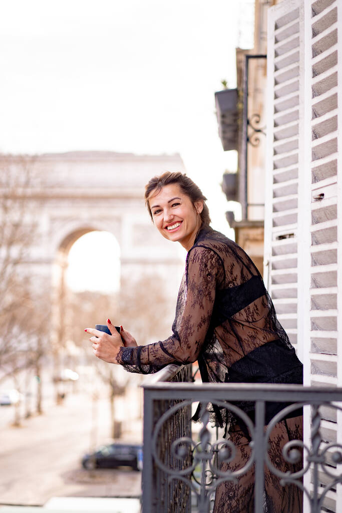 Atraktivní jang žena v pyžamu pije kávu na balkóně  - Fotografie, Obrázek