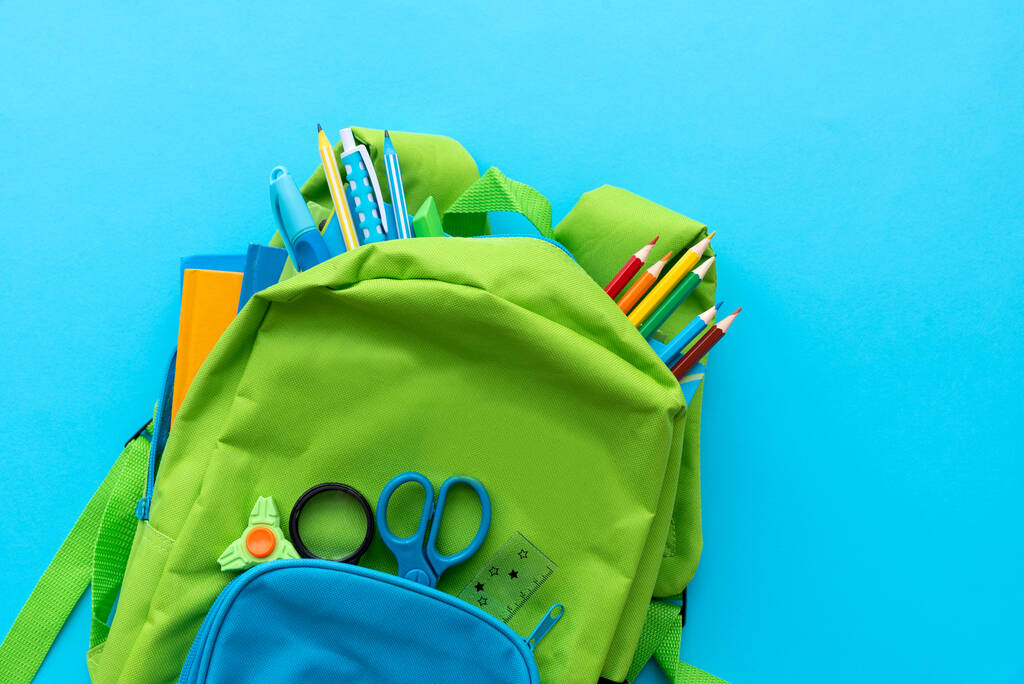 Okul konseptine geri dönelim. BLUE arka planında okul malzemeleri olan sırt çantası. Üst Manzara. Boşluğu kopyala - Fotoğraf, Görsel