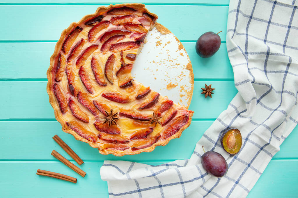 Вкусный фруктовый пирог со сливками на бирюзовом столе, вкусный летний десерт, вид сверху
.   - Фото, изображение